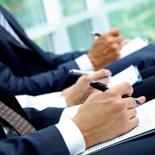 Close-up of business people hands with papers writing at lecture